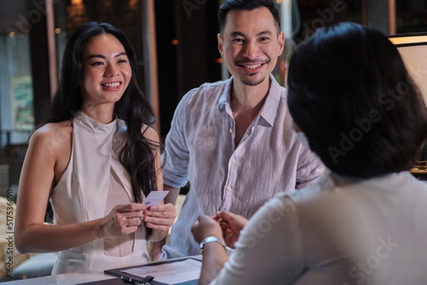 Fototapeta Business partners or couple and receptionist at counter in hotel. Young couple doing check-in at the hotel and receiving room key