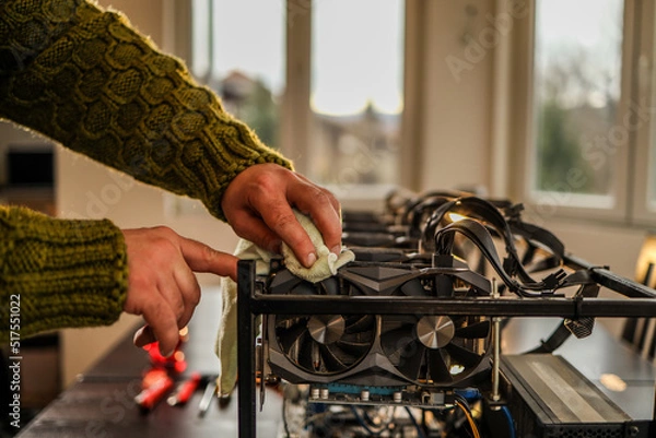 Fototapeta Man wiping cryptocurrency mining rig with rag
