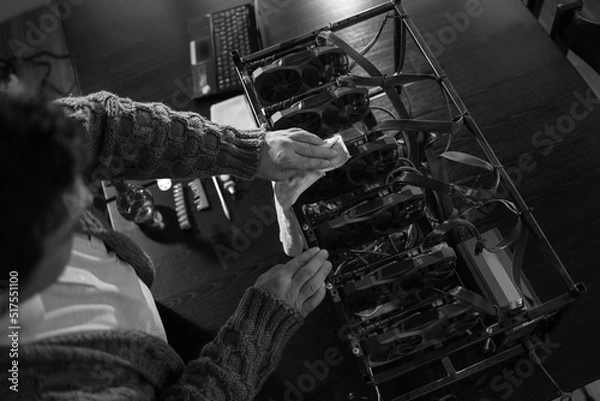 Fototapeta Man wiping cryptocurrency mining rig with rag