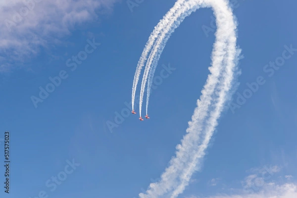 Fototapeta three red planes make a loop in the blue sky