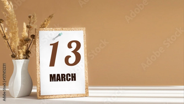 Fototapeta march 13. 13th day of month, calendar date.White vase with dead wood next to cork board with numbers. White-beige background with striped shadow. Concept of day of year, time planner, spring month