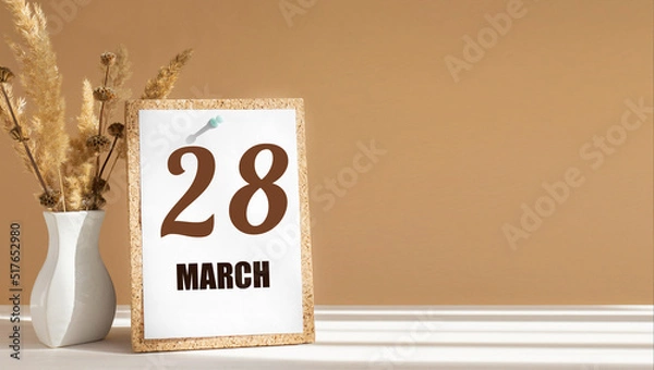Fototapeta march 28. 28th day of month, calendar date.White vase with dead wood next to cork board with numbers. White-beige background with striped shadow. Concept of day of year, time planner, spring month