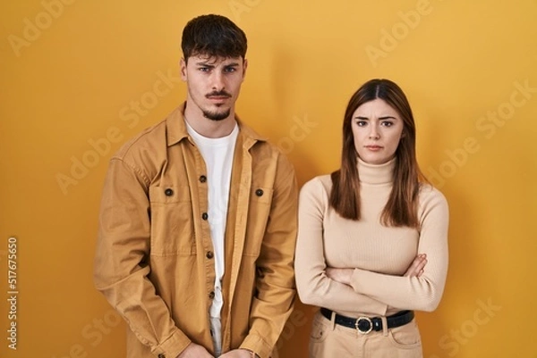 Fototapeta Young hispanic couple standing over yellow background skeptic and nervous, frowning upset because of problem. negative person.