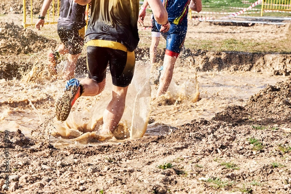 Fototapeta Group of participants in an obstacle course race running across a pool of water. Spartan race