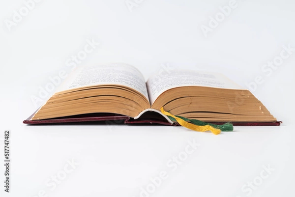 Fototapeta On a white background, an open old book with bookmarks. The concept of study, wisdom.