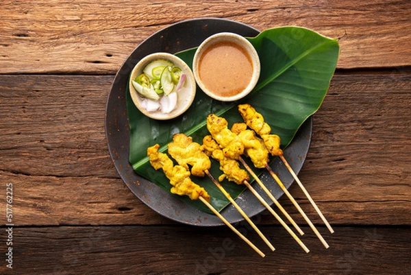 Fototapeta Thai Pork Satay, Moo Satay Grilled pork served with peanut sauce or sweet and sour sauce - Asian food Concept style on wooden table background. Top view