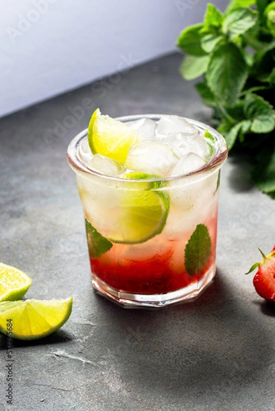 Fototapeta cold detox water with lime, strawberry, mint in the glass with ice cubes on gray background. close up
