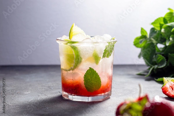 Fototapeta cold detox water with lime, strawberry, mint in the glass with ice cubes on gray background. copy space