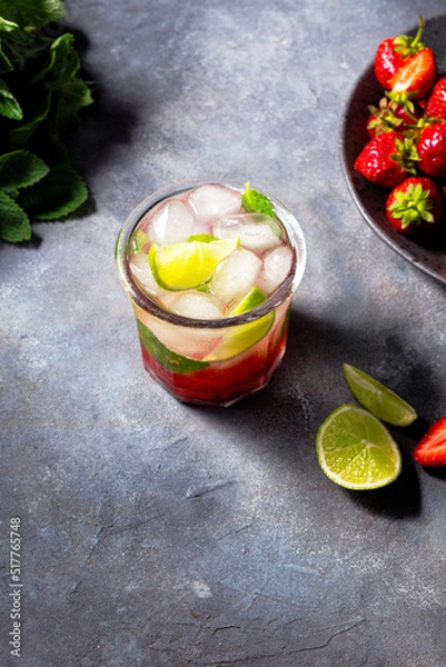 Fototapeta cold detox water with lime, strawberry, mint in the glass with ice cubes on gray background. copy space