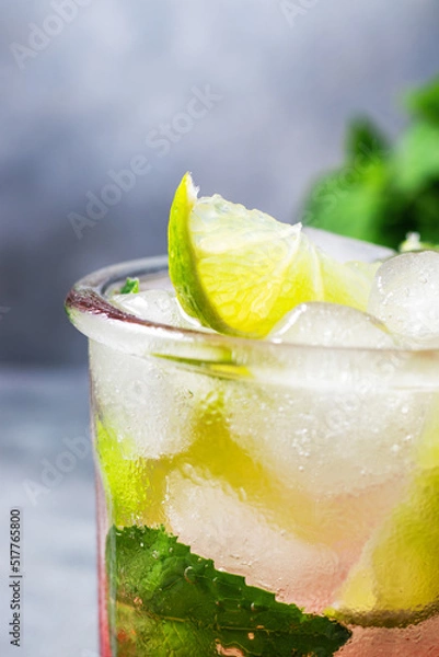 Fototapeta cold detox water with lime, strawberry, mint in the glass with ice cubes on gray background. close up