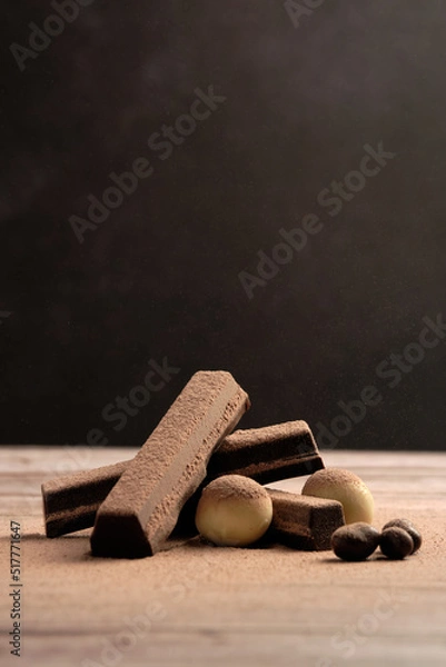 Fototapeta delicious mountain of dark, white and milk chocolate. powdered chocolate on top. vertical picture. international chocolate day.