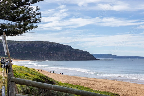 Obraz Seaside road winding along calm beach and rocky headland on sunny day
