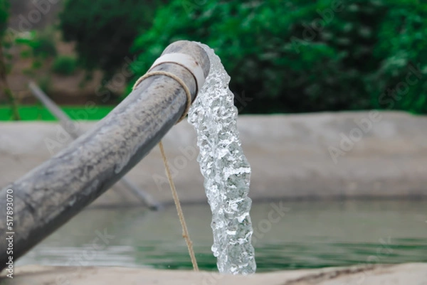 Obraz Pumping water out of plastic pipe into the ground,Water from a well filled a pond for irrigation,Irrigation water from the source,Water flow from large pump tube in Farm,being flush out a heavy tube,