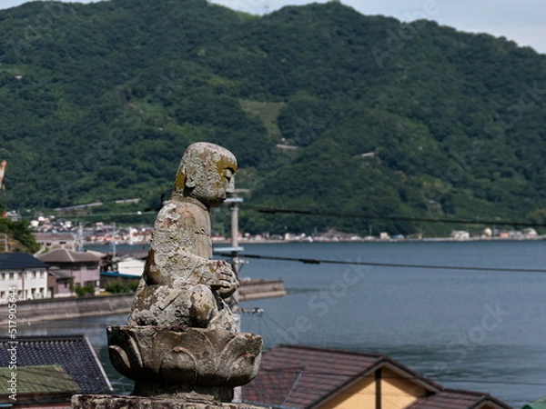 Obraz 港を見下ろす丘に座る石の仏像

