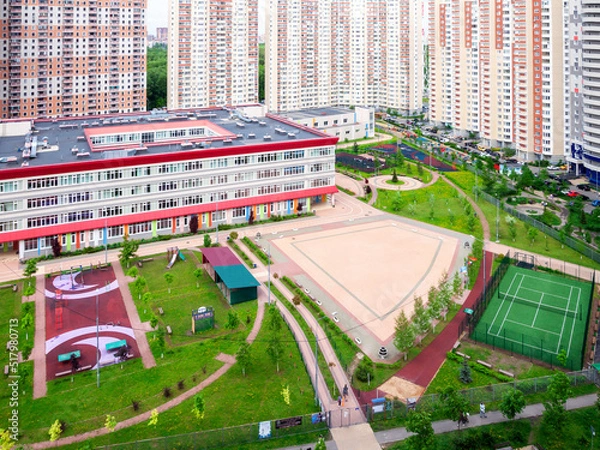 Fototapeta Public school building. Exterior view of school building with playground mixed-use urban multi-family residential district area development. Back to school concept.