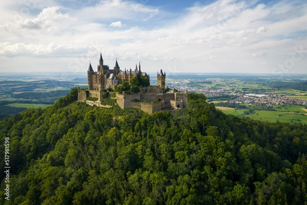 Fototapeta Drone shot of Hohenzollern Castle on forested mountain top in the Swabian Alps in summer. Scenic aerial view of old German Burg. Famous fairytale Gothic landmark in Stuttgart vicinity