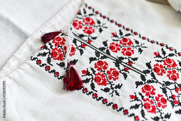 Fototapeta Fragment of Ukrainian national dress. Vyshyvanka - ethnic clothing with embroidery patterns. red and black threads. Close-up shot, copy space.