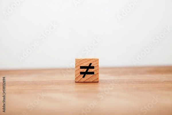 Obraz ノットイコールの記号。≠。等しくない。木製ブロックに書かれている。黒い文字。木製テーブルの背景。