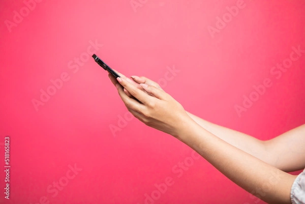 Obraz Woman hand Holding smartphone scroll and touch display on pink background.