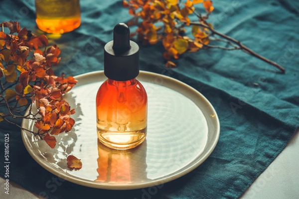 Fototapeta Vitamin C serum in a bottle with a pipette on a round dish. The concept of anti-acid skin care.