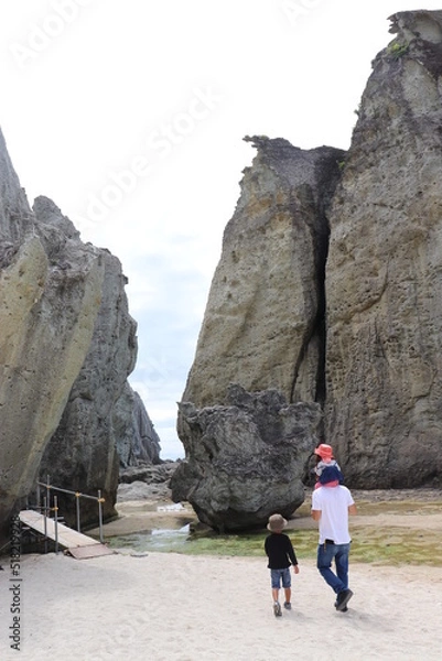 Fototapeta 大きな岩の間を歩いていく親子