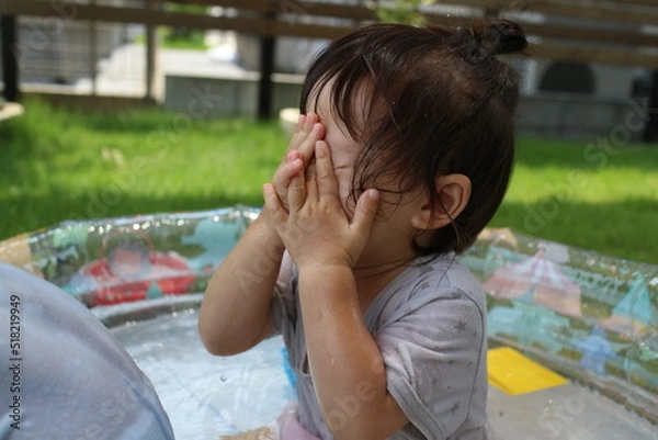 Obraz 顔に水がかかって手でおさえる小さな女の子