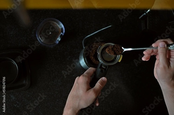 Obraz Americano brew. A man pours coffee into a coffee machine. Ground coffee. Shooting from above.
