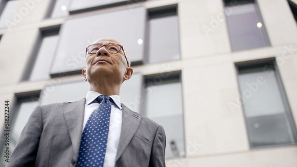 Fototapeta Portrait of successful senior Asian business man looking outward from a low angle