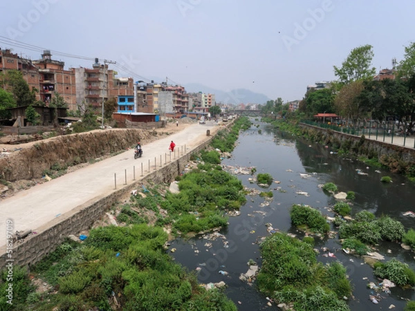 Fototapeta Contaminated river runs through city. waste is discarded river bank. lack of waste collection services. Kathmandu, Nepal, Asia