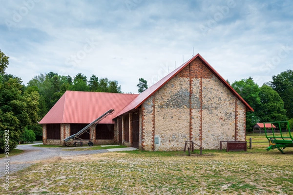 Fototapeta A beautiful large barn at the horse farm in Florianka. Red corrugated metal sheet on the roof of the barn