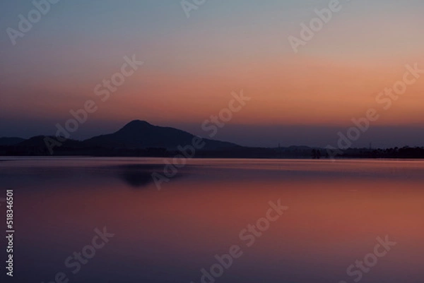 Fototapeta Dramatic hued skyline of Barhanti (Baranti) Hill and adjoining Baranti lake just after sunset. The lake is a man-made water reservoir. It is a popular travel destination in Purulia district of Bengal.