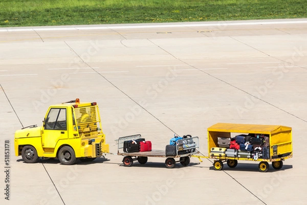 Obraz Yellow Freight trolleys with loaded baggage on the runway tarmac