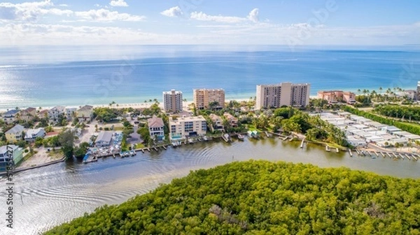 Fototapeta Aerial Drone View of Bonita Springs Beach, Florida with the Bay and Mangroves in the Foreground and the Gulf of Mexico in the Background 