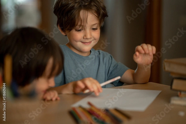 Fototapeta Two little boys, two brothers are sitting at home at the table and drawing with colored pencils. Child and creativity