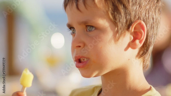 Fototapeta 4 sibling boys look at the camera smiling, play while running through a restaurant in front of the camera, eat ice cream, hug their mother