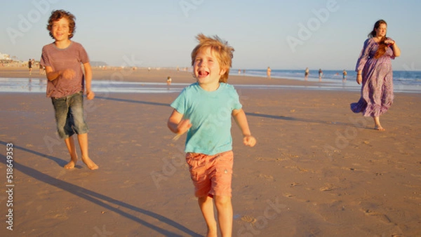 Fototapeta Wonderful family - father, mother and 4 sons (1-8 years old) - walk along one of the most beautiful beaches of Cádiz at sunset - they love and hug each other, look after their children