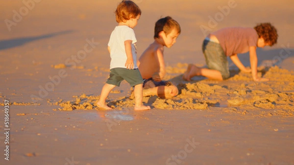 Fototapeta Wonderful family - father, mother and 4 sons (1-8 years old) - walk along one of the most beautiful beaches of Cádiz at sunset - they love and hug each other, look after their children