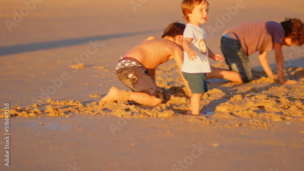 Fototapeta Wonderful family - father, mother and 4 sons (1-8 years old) - walk along one of the most beautiful beaches of Cádiz at sunset - they love and hug each other, look after their children