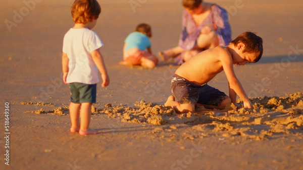 Fototapeta Wonderful family - father, mother and 4 sons (1-8 years old) - walk along one of the most beautiful beaches of Cádiz at sunset - they love and hug each other, look after their children