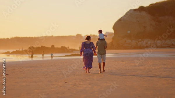 Fototapeta Wonderful family - father, mother and 4 sons (1-8 years old) - walk along one of the most beautiful beaches of Cádiz at sunset - they love and hug each other, look after their children