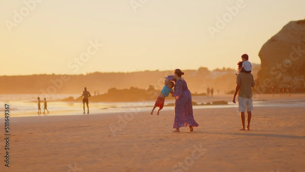 Fototapeta Wonderful family - father, mother and 4 sons (1-8 years old) - walk along one of the most beautiful beaches of Cádiz at sunset - they love and hug each other, look after their children