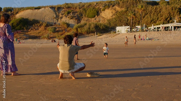 Fototapeta Wonderful family - father, mother and 4 sons (1-8 years old) - walk along one of the most beautiful beaches of Cádiz at sunset - they love and hug each other, look after their children