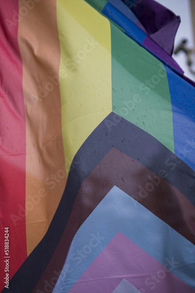Fototapeta Close Up rainbow gay pride flag outside on a street. Symbol of the Lesbian Bisexual Transgender LGBT community waving in wind against cloudy sky. Social movement for freedom and equliaty. Copy Space