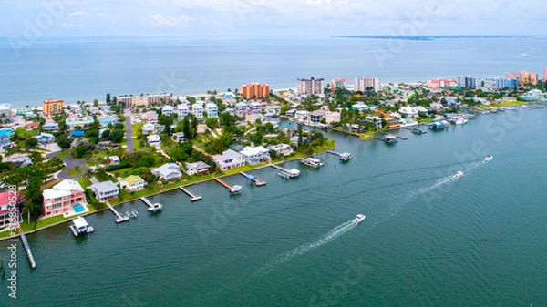 Fototapeta Aerial Drone View of Homes Featuring Docks on Blue Bay Waters Surrounded by Mangroves in Naples, Florida and the Gulf of Mexico in the Background with a Clear Sky