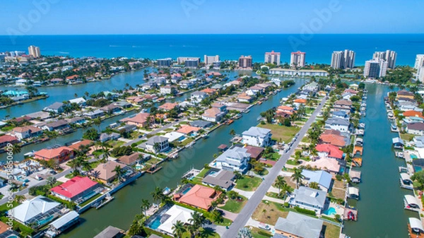 Fototapeta Aerial View of Homes on Canals and Waterways in Naples, Florida with the Gulf of Mexico and the Beach in the Background Giving a Great Drones Eye View of Real Estate and Nature