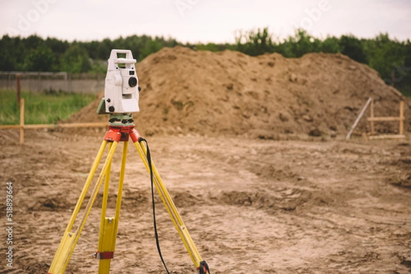 Obraz Surveyor equipment - GPS system or theodolite total positioning system outdoors at house construction site. Surveyor engineering with total station before house building