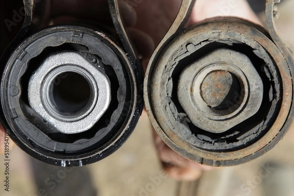 Fototapeta New and old defective silent blocks with metall sleeves close up. Car suspension arm diagnostic service