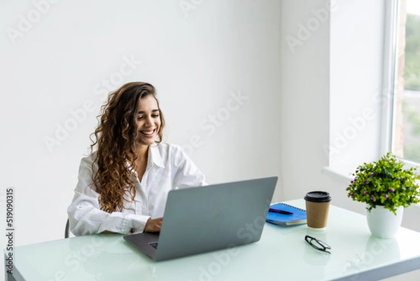 Fototapeta Young beautiful joyful woman smiling while working with laptop in office
