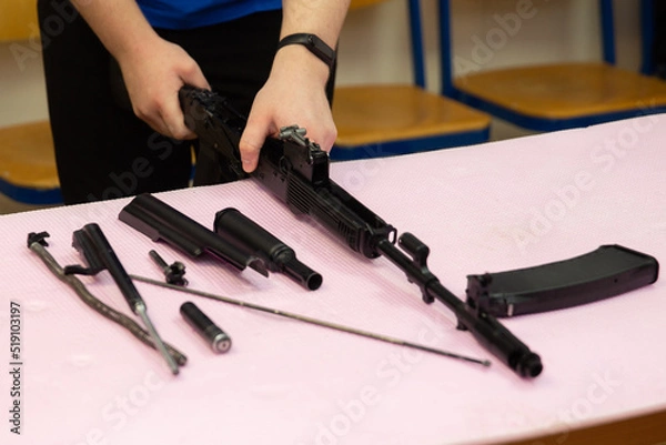 Fototapeta Assembling and disassembling a Kalashnikov assault rifle on a table. Details of the Kalashnikov assault rifle
