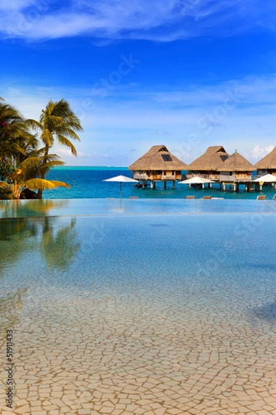 Obraz seacoast with palm trees and small houses on water.